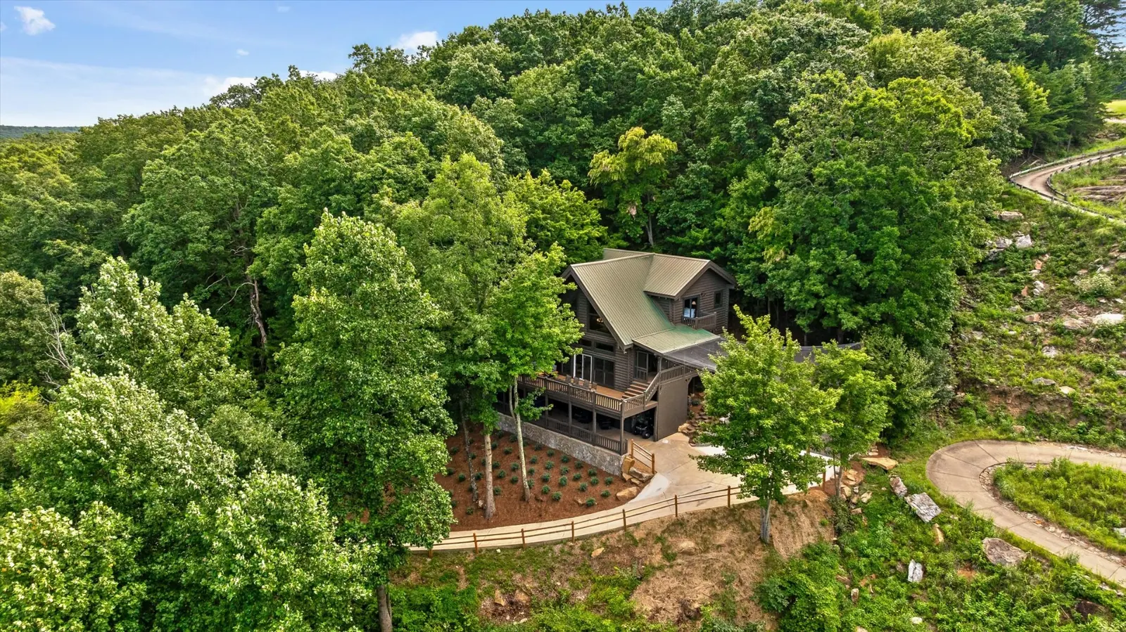Aerial view of the Eyrie House, a dark timber cabin with a standing-seam metal roof, tucked into the hardwoods at McLemore on Lookout Mountain