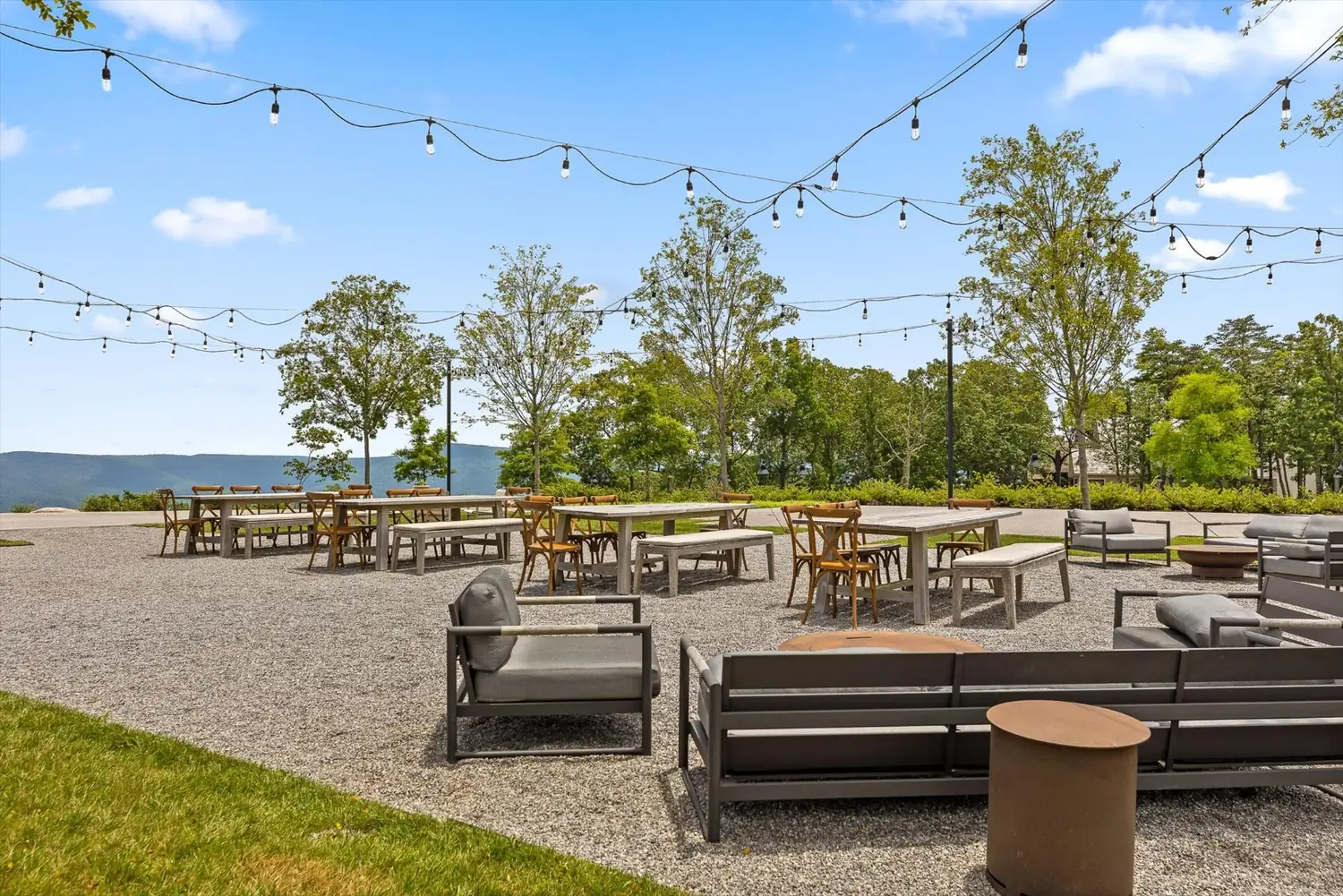 Outdoor lounge seating around a fire pit with string lights above