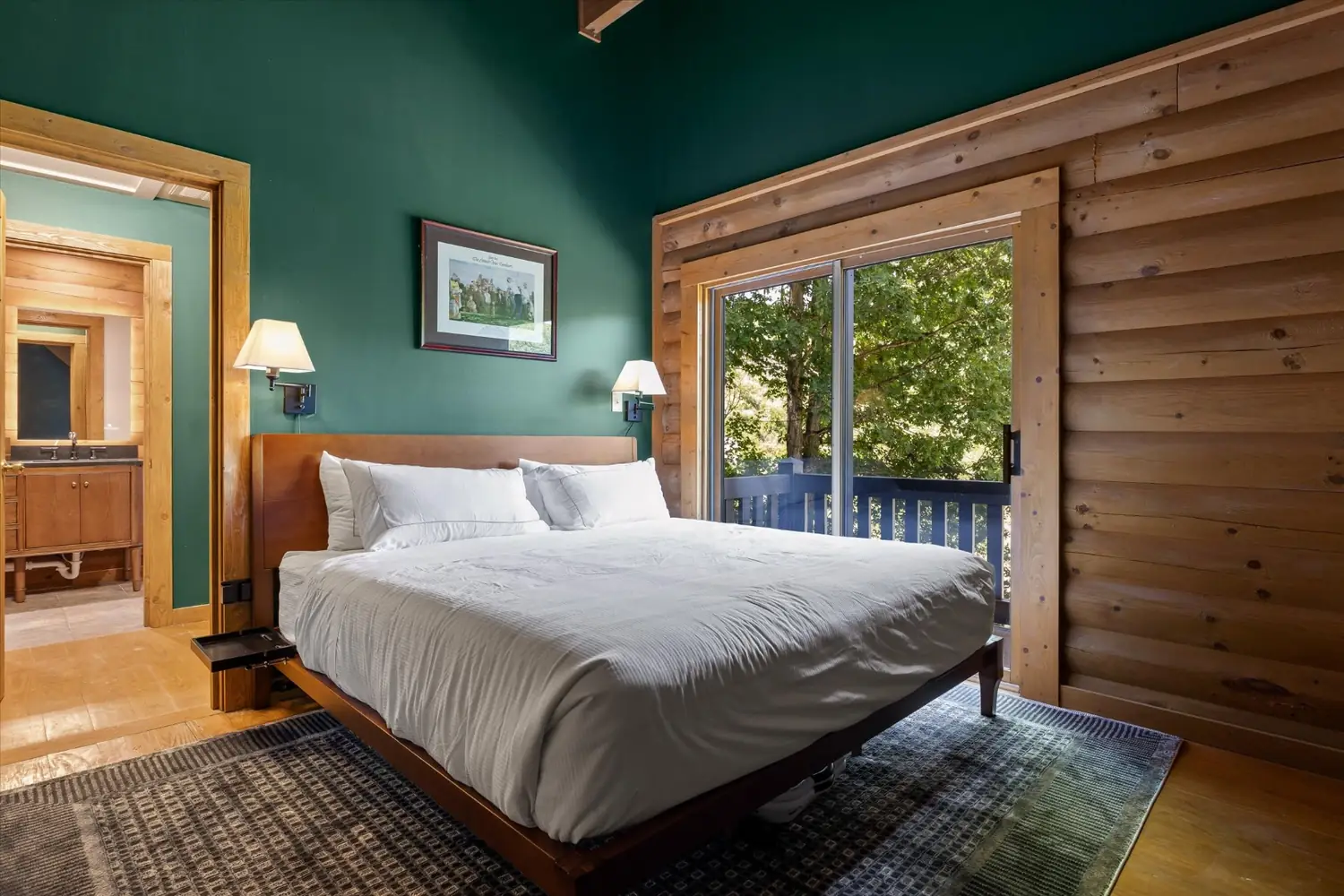A deep green bedroom with a king bed and mountain light