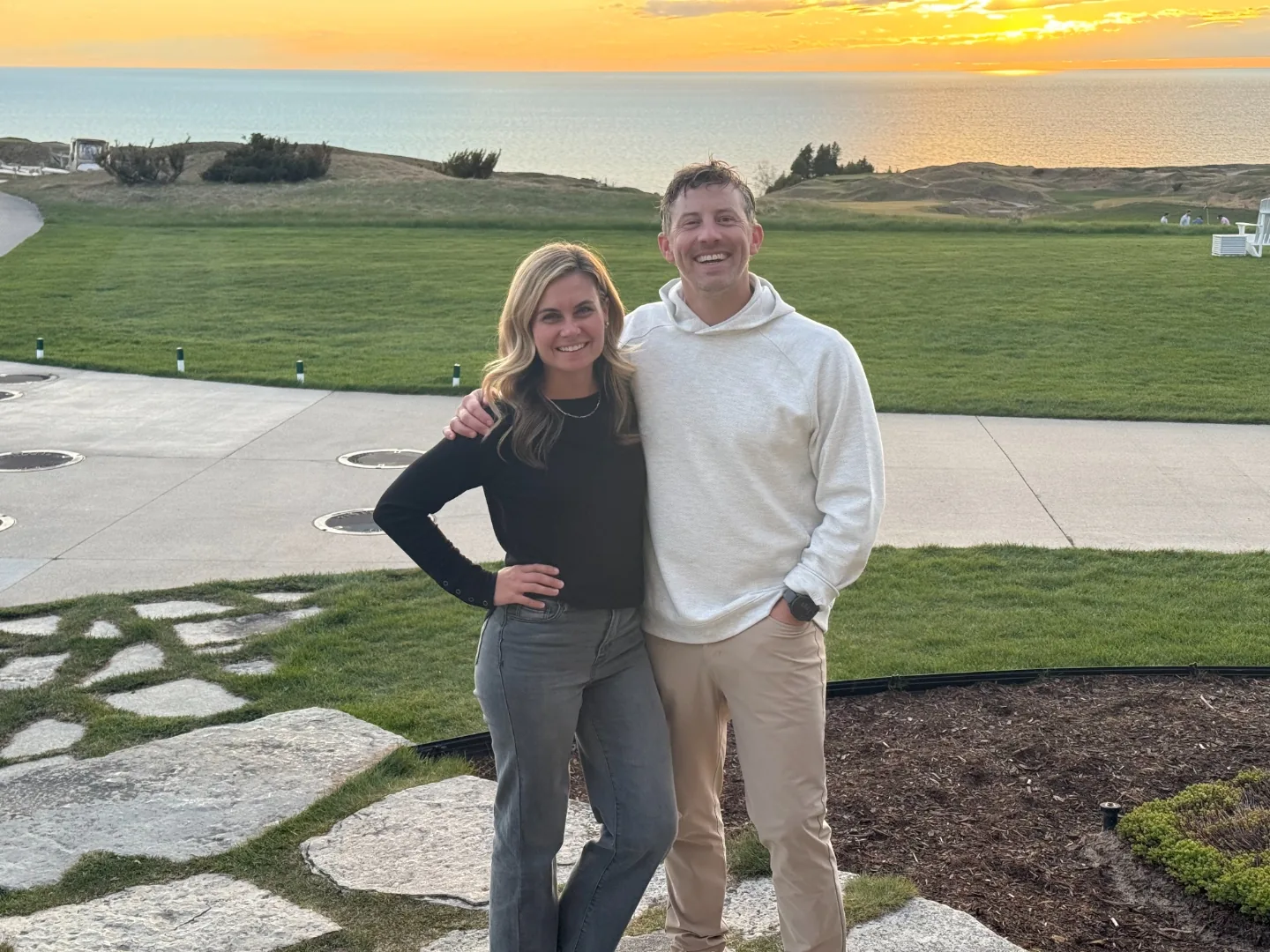 Jeff and Chelsea at sunset on the bluff at Arcadia Bluffs, with the fairway, dune grass and Lake Michigan glowing behind them